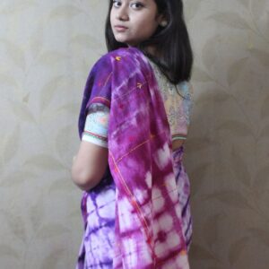 Model wearing a hand-dyed violet and magenta Shibori tie-dye saree with minimal embroidery.